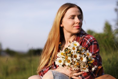 Photo of Beautiful woman with wildflowers enjoying summer day in meadow. Space for text