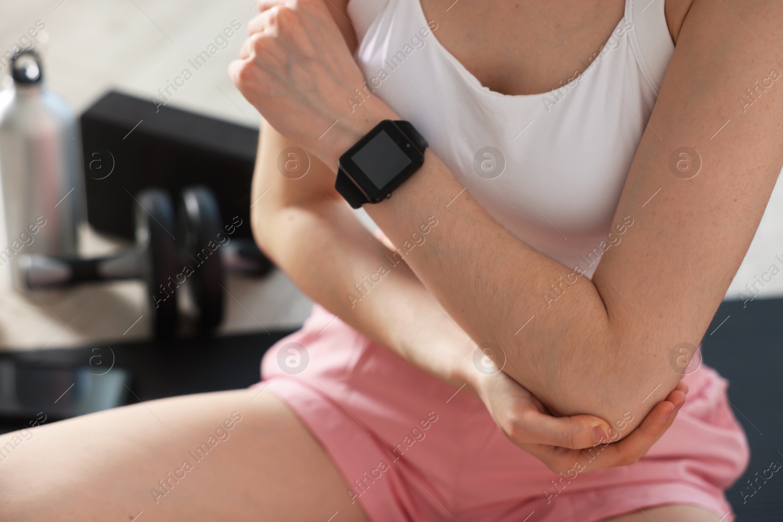 Sports injury. Young woman suffering from elbow pain in fitness studio, closeup Photo of Sports injury. Young woman suffering from elbow pain in fitness studio, closeup