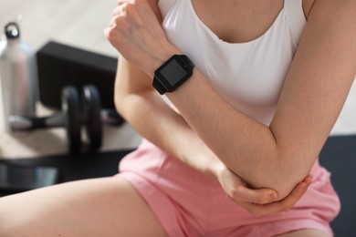 Photo of Sports injury. Young woman suffering from elbow pain in fitness studio, closeup