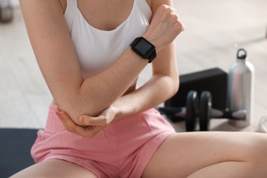 Photo of Sports injury. Young woman suffering from elbow pain in fitness studio, closeup