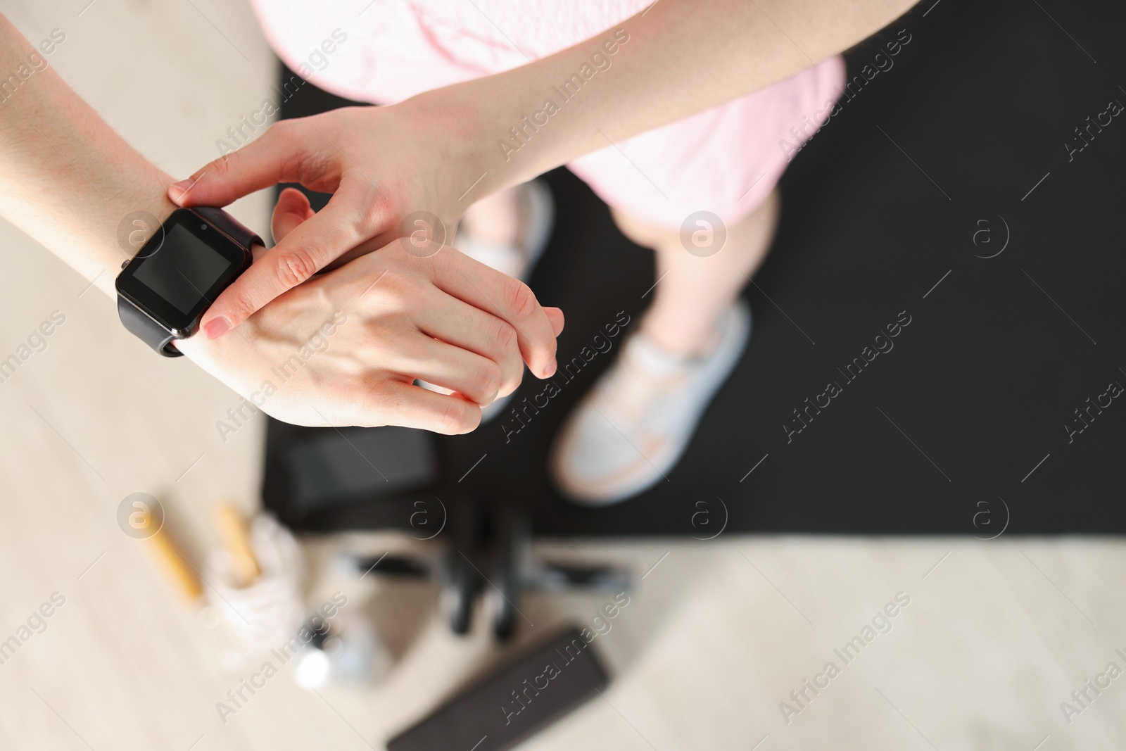 Photo of Woman checking fitness tracker during training indoors, closeup