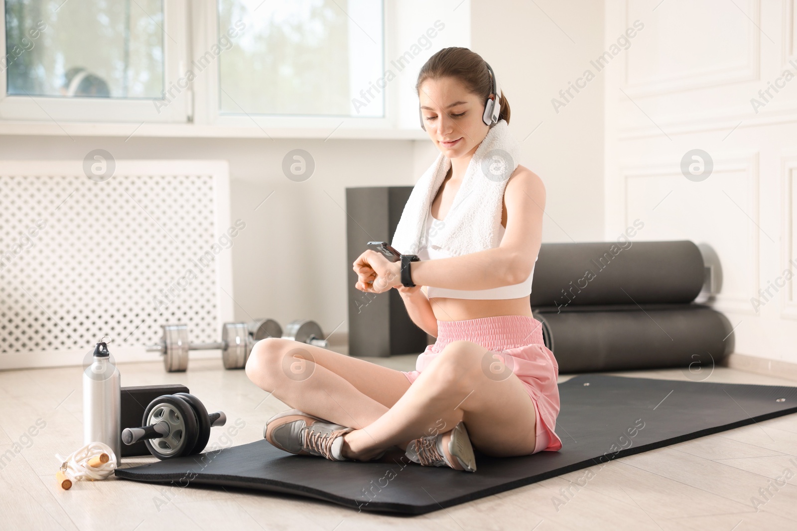 Woman checking fitness tracker during training indoors Photo of Woman checking fitness tracker during training indoors