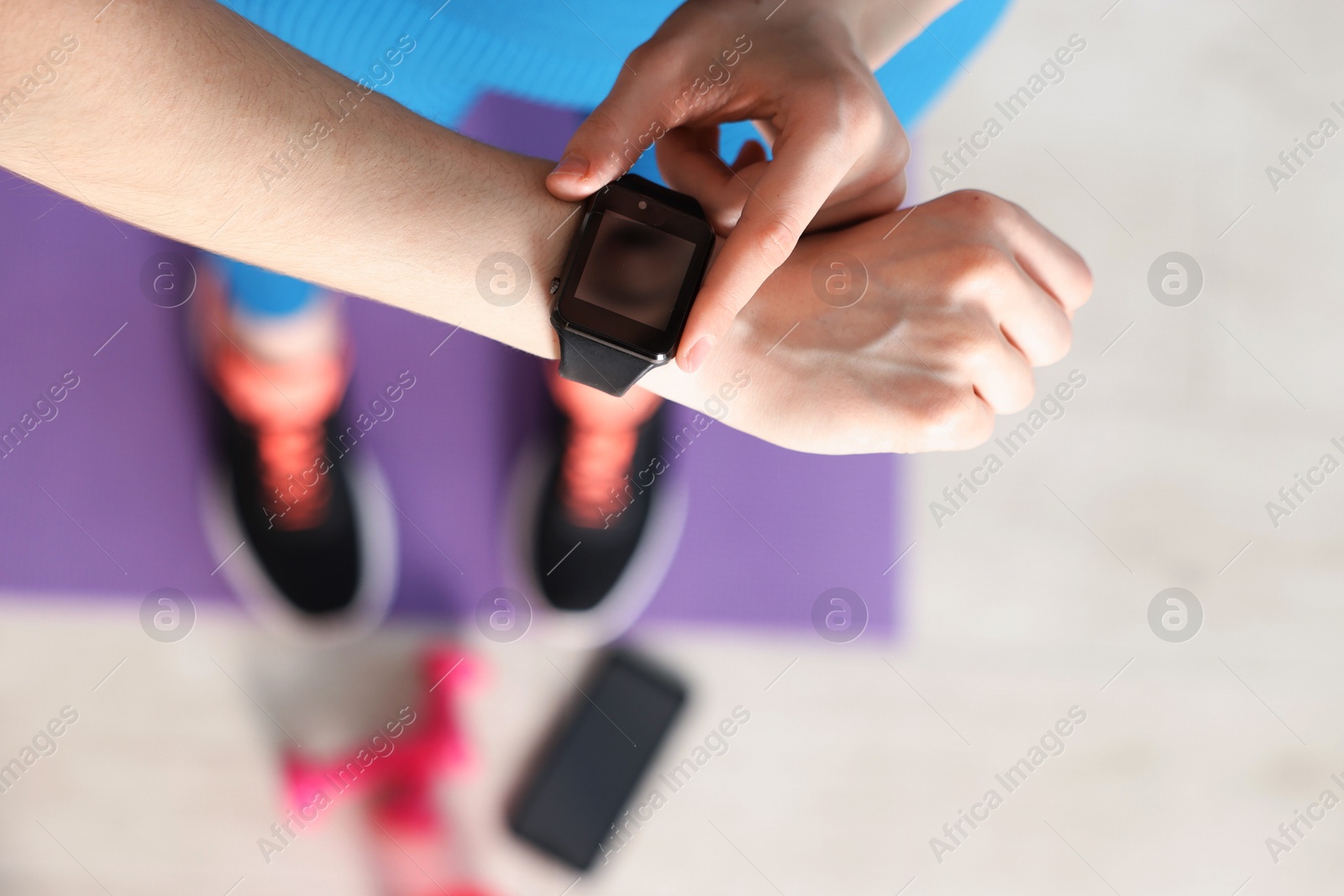 Woman checking fitness tracker during training indoors, above view Photo of Woman checking fitness tracker during training indoors, above view