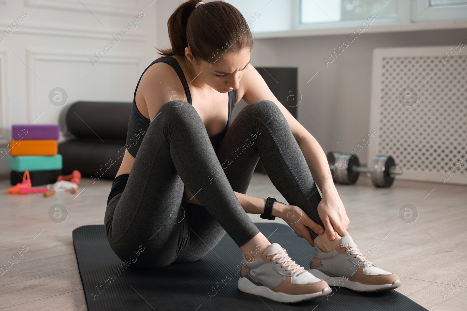 Sports injury. Young woman suffering from leg pain in fitness studio Photo of Sports injury. Young woman suffering from leg pain in fitness studio