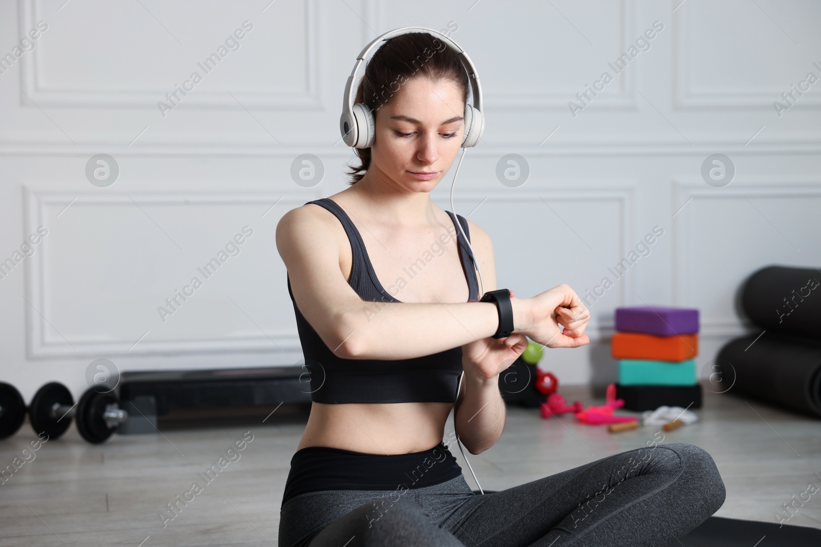 Photo of Woman checking fitness tracker during training indoors
