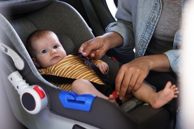 Photo of Mother fastening her baby in car seat, closeup