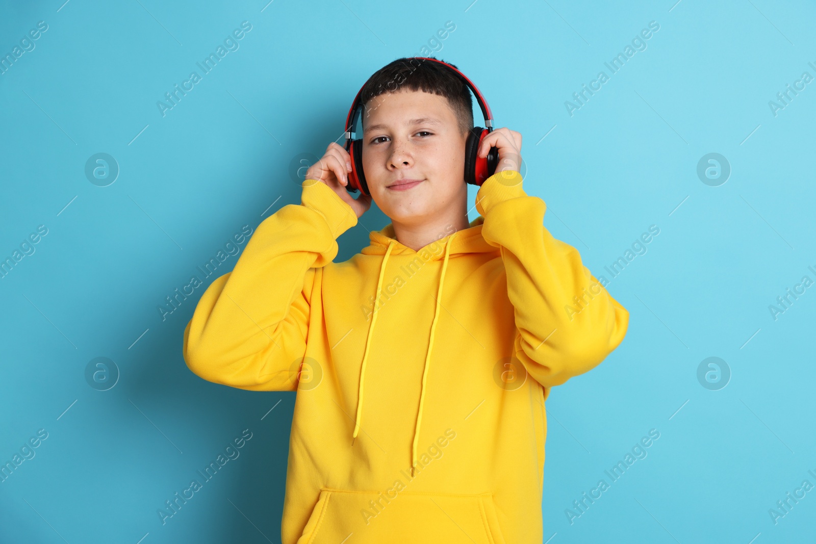 Photo of Teenage boy in headphones on light blue background