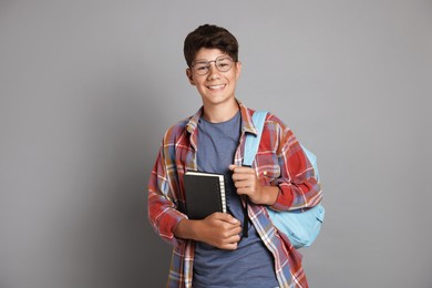 Photo of Teenage boy with notebook and backpack on grey background