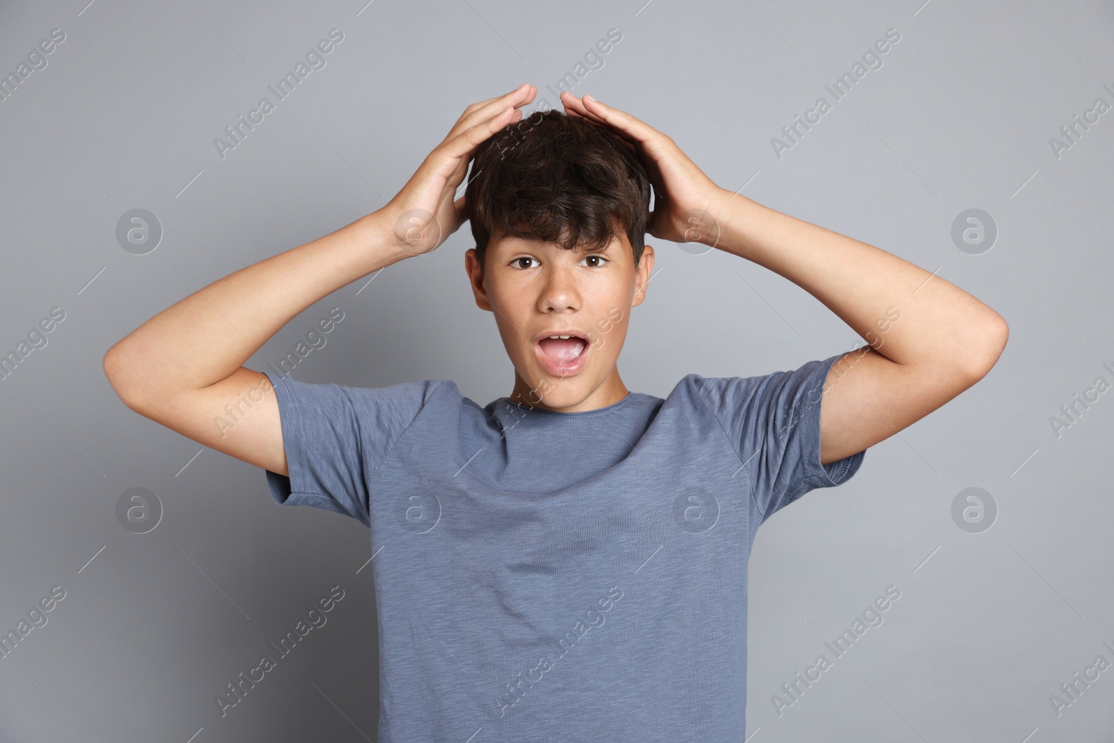 Portrait of surprised teenage boy on grey background Photo of Portrait of surprised teenage boy on grey background