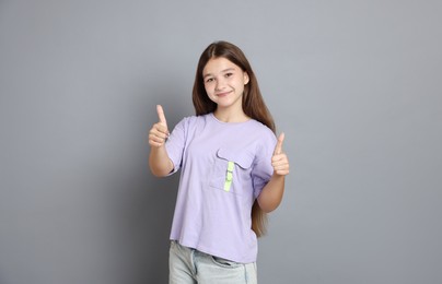 Photo of Teenage girl showing thumbs up on grey background