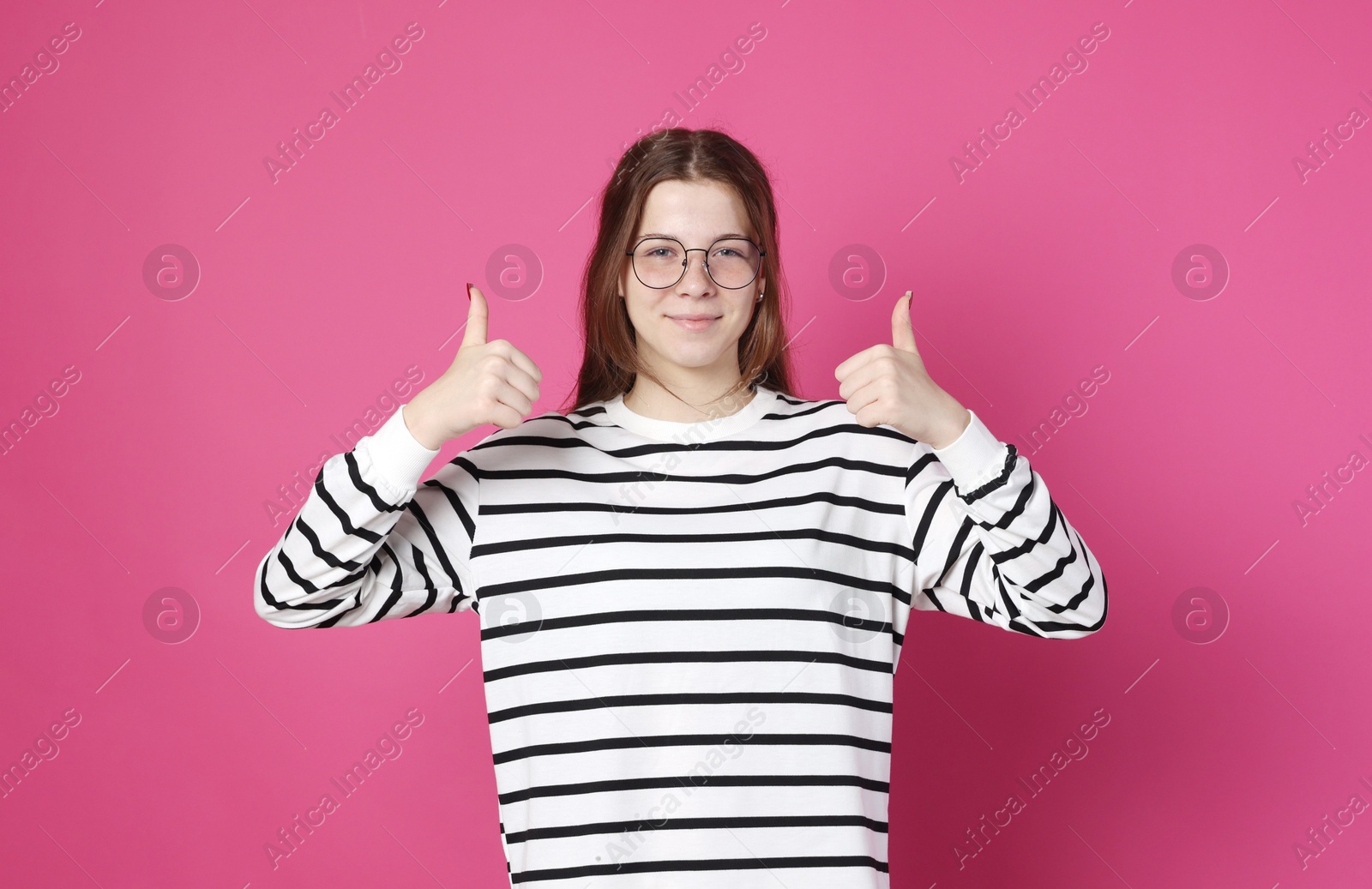 Photo of Teenage girl in glasses showing thumbs up on crimson background