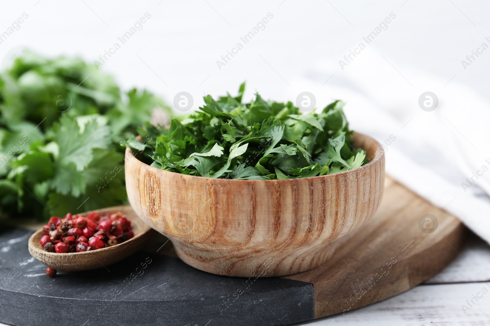 Photo of Fresh green cilantro and peppercorns on white wooden table, closeup