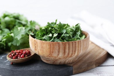 Photo of Fresh green cilantro and peppercorns on white wooden table, closeup