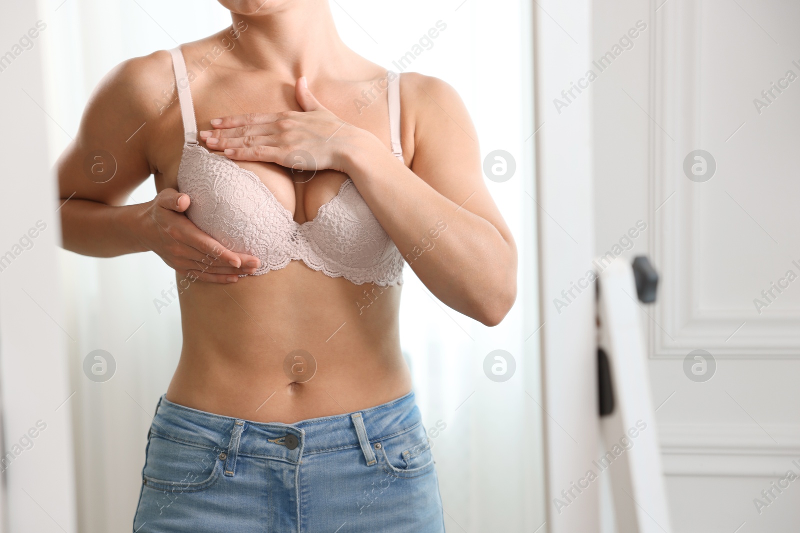Woman wearing beautiful bra near mirror indoors, closeup Photo of Woman wearing beautiful bra near mirror indoors, closeup