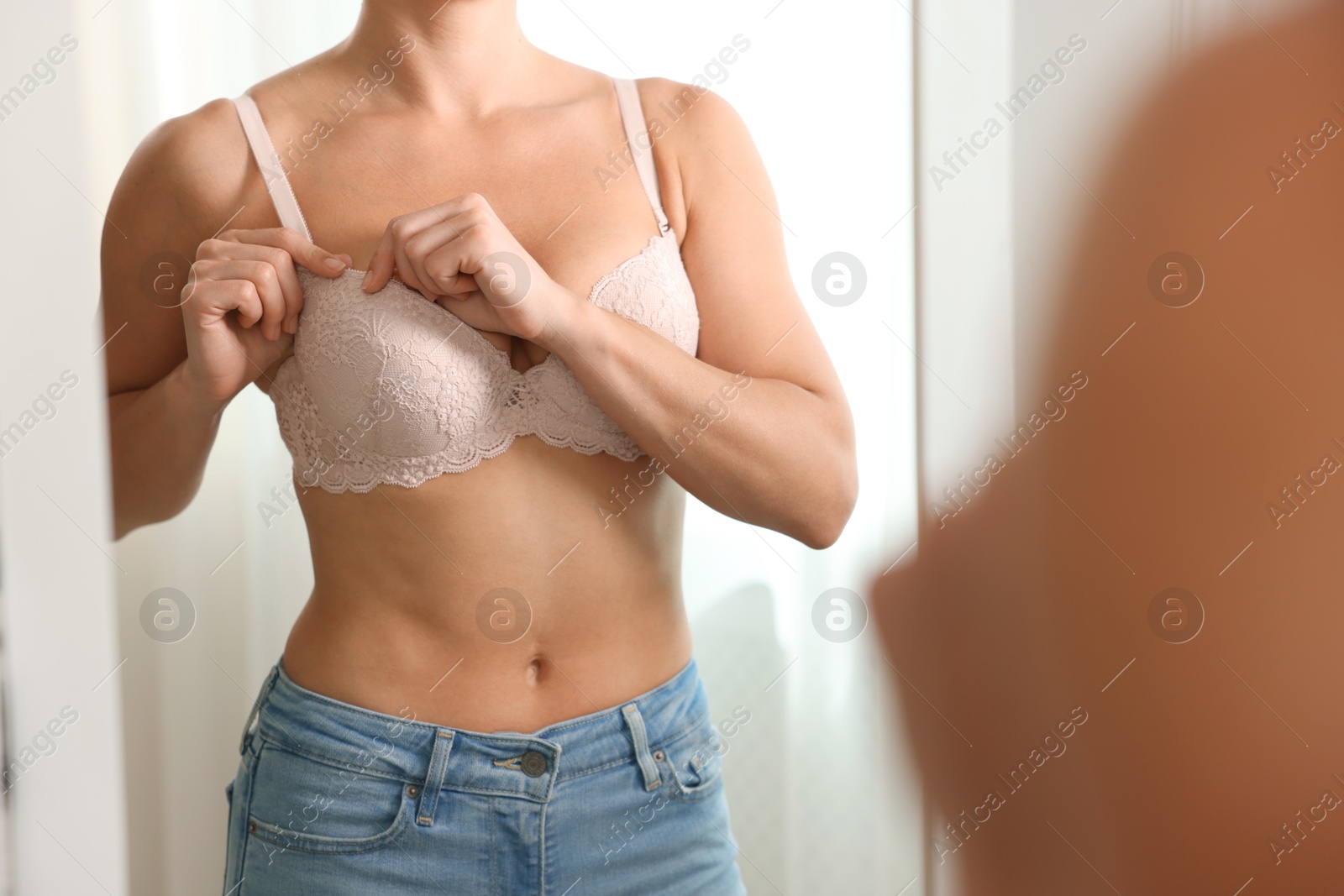 Woman wearing beautiful bra near mirror indoors, closeup Photo of Woman wearing beautiful bra near mirror indoors, closeup