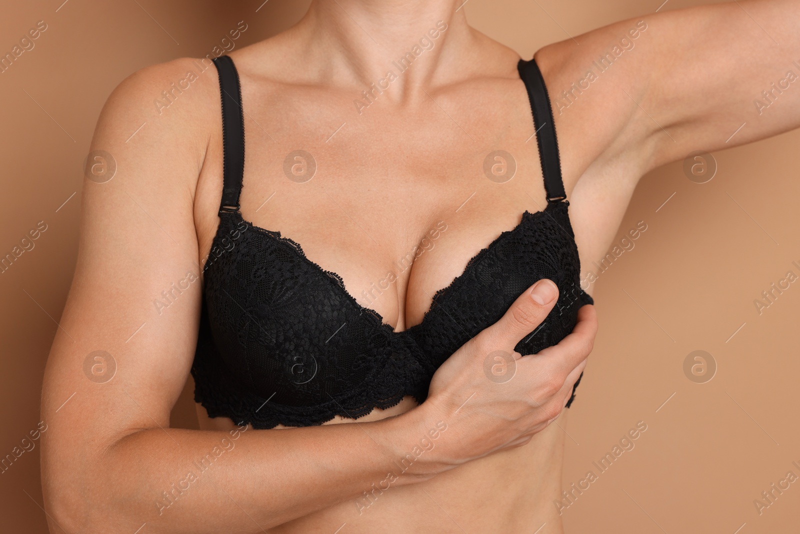 Woman wearing beautiful black bra on beige background, closeup Photo of Woman wearing beautiful black bra on beige background, closeup