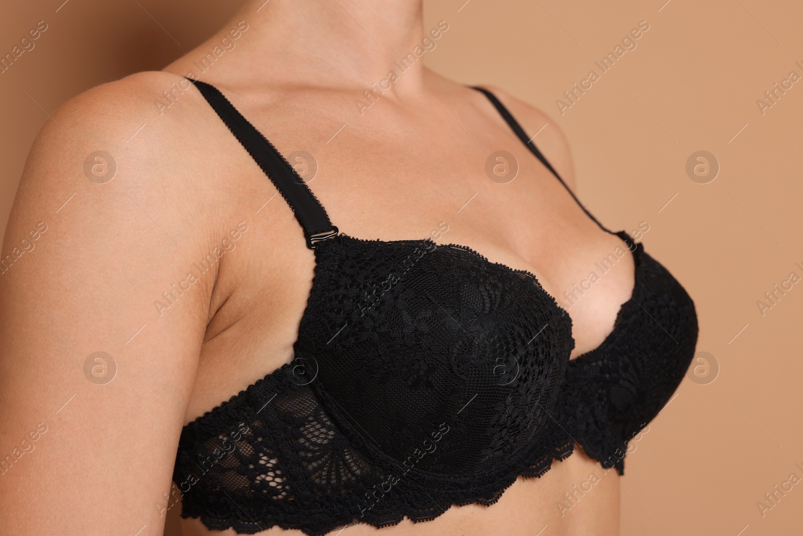 Woman wearing beautiful black bra on beige background, closeup Photo of Woman wearing beautiful black bra on beige background, closeup