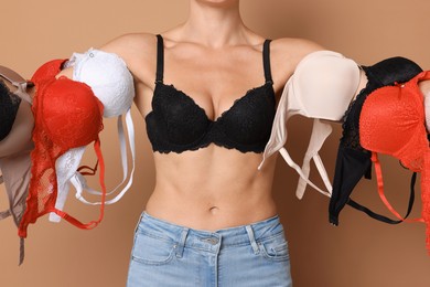Photo of Woman with different beautiful bras on beige background, closeup
