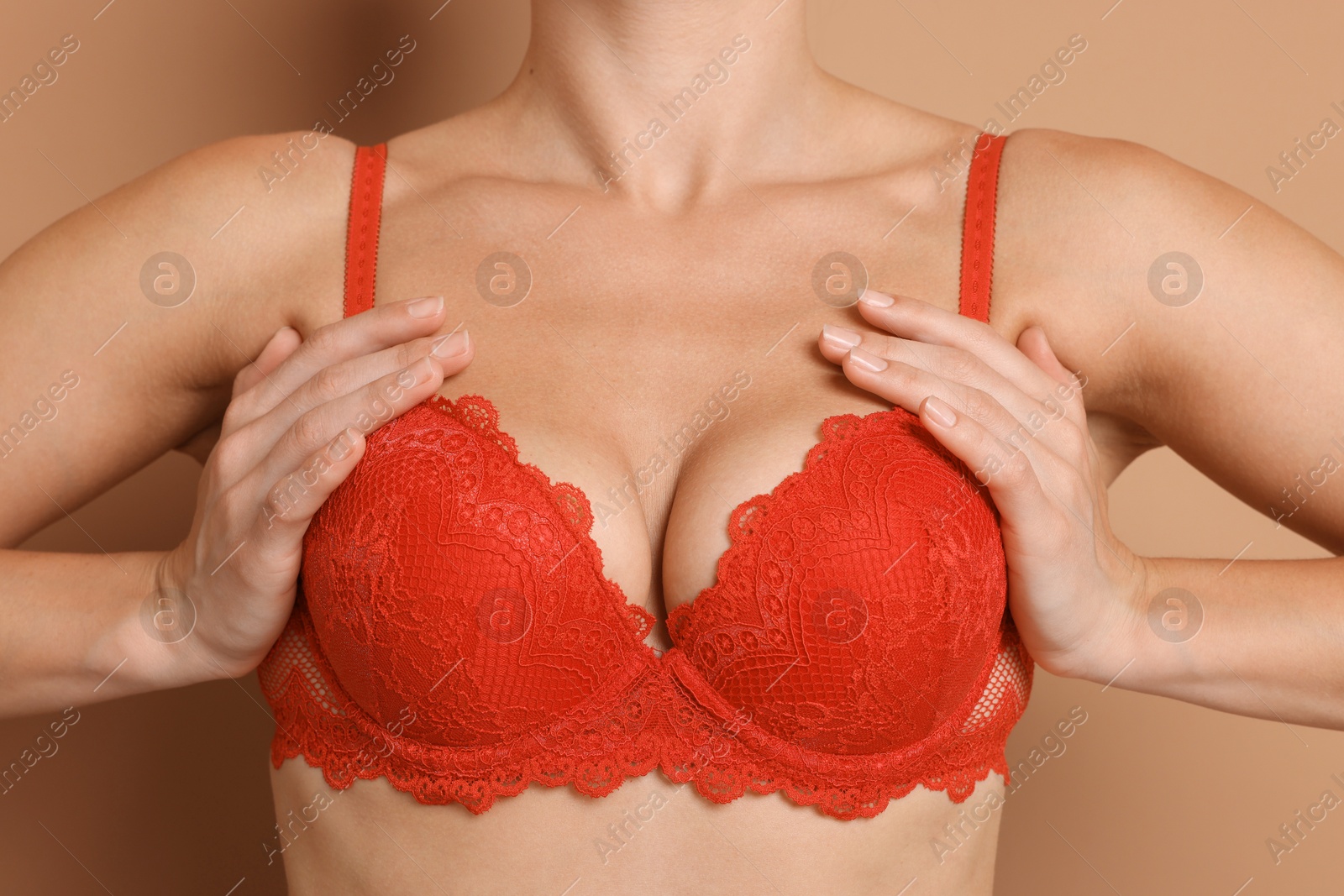 Photo of Woman wearing beautiful red bra on beige background, closeup