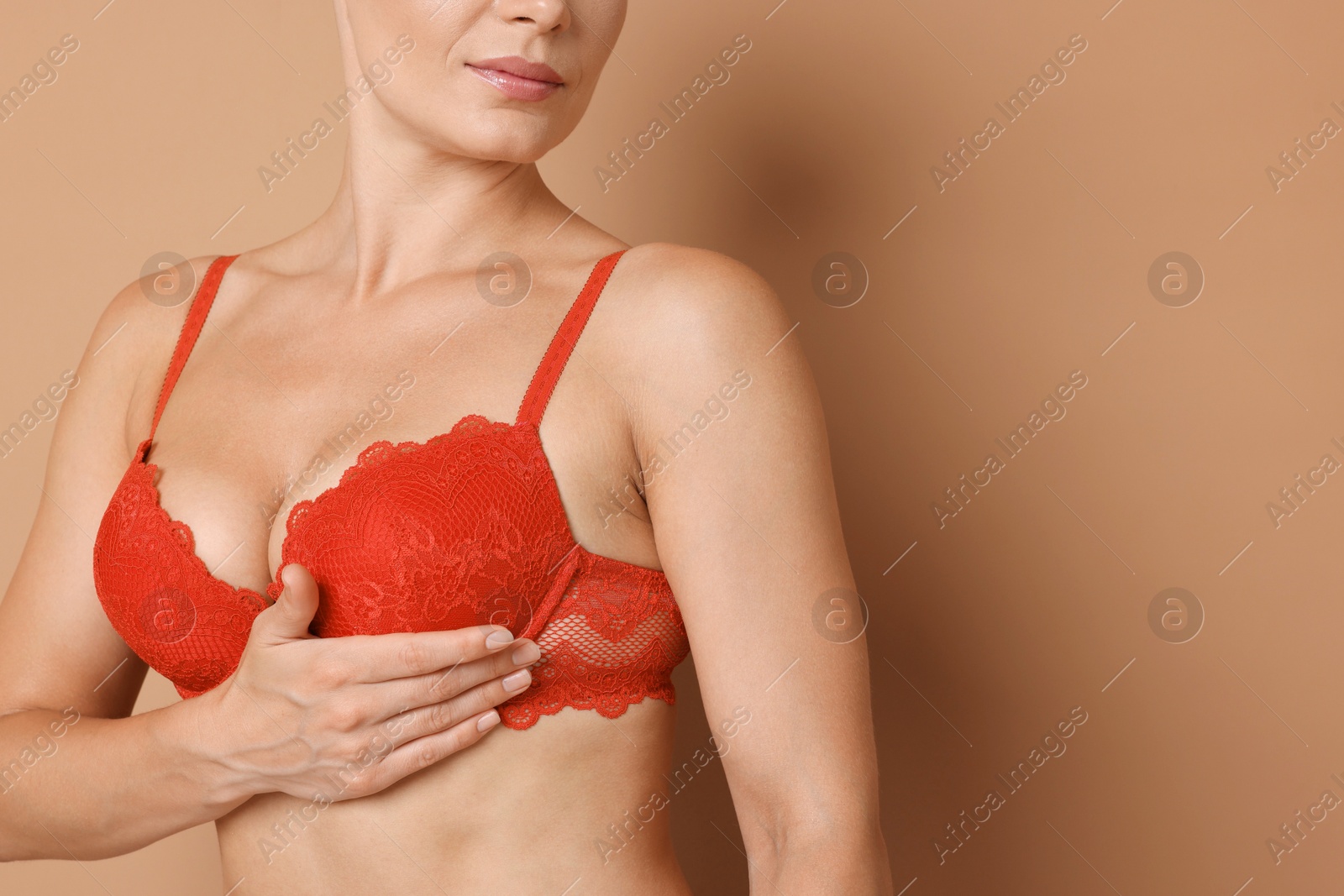 Woman wearing beautiful red bra on beige background, closeup. Space for text Photo of Woman wearing beautiful red bra on beige background, closeup. Space for text