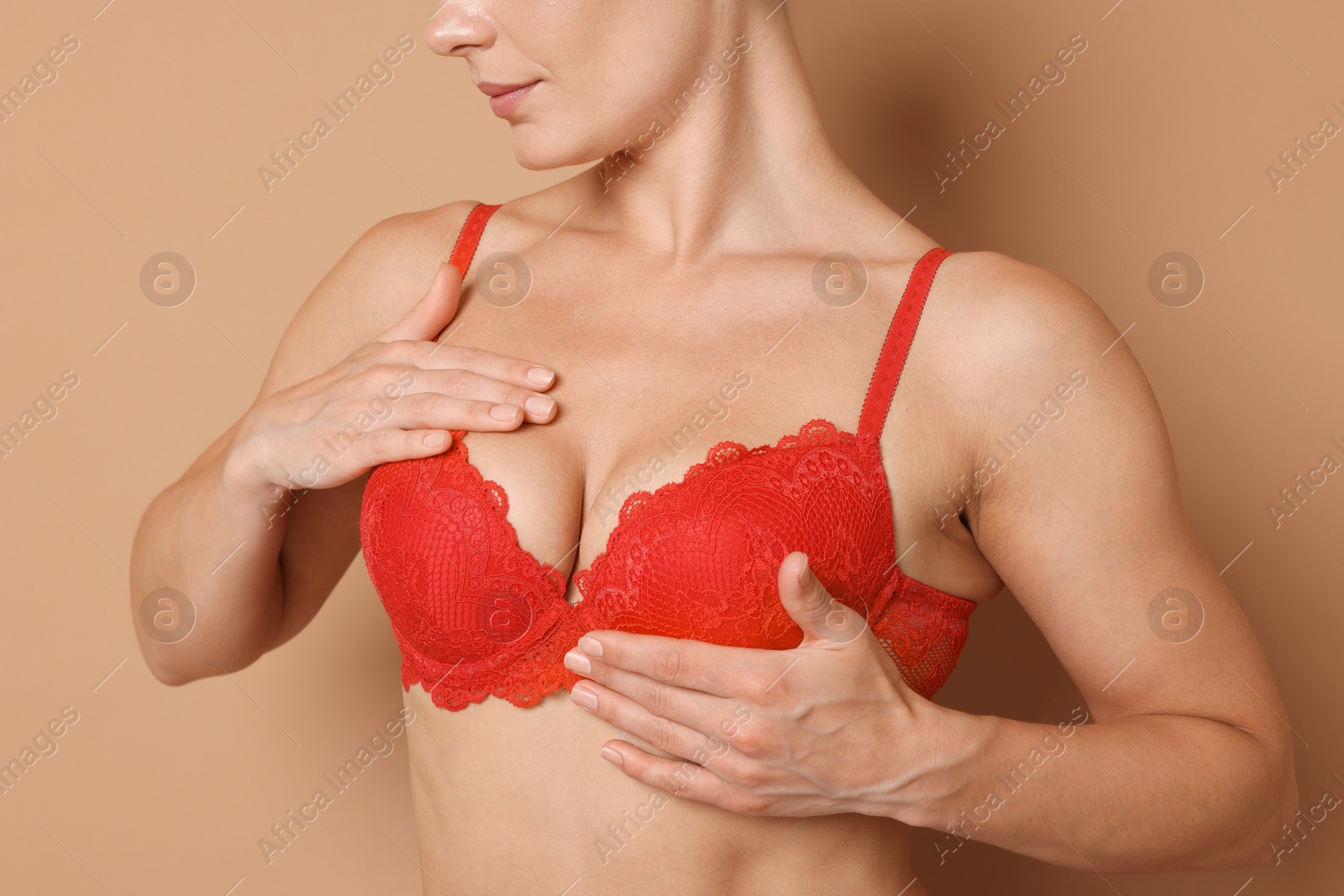 Woman wearing beautiful red bra on beige background, closeup Photo of Woman wearing beautiful red bra on beige background, closeup