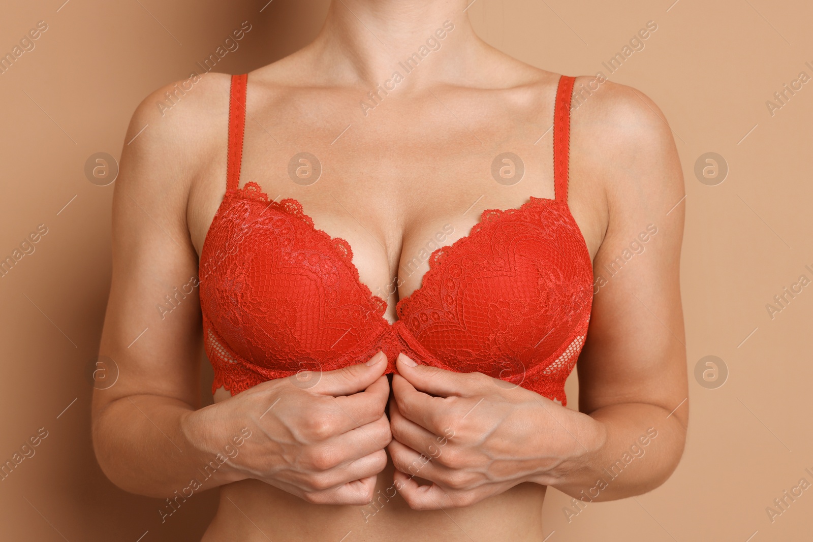 Photo of Woman wearing beautiful red bra on beige background, closeup