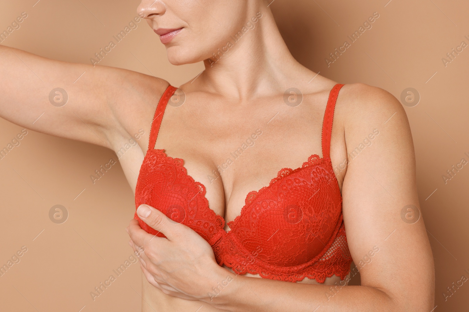 Woman wearing beautiful red bra on beige background, closeup Photo of Woman wearing beautiful red bra on beige background, closeup