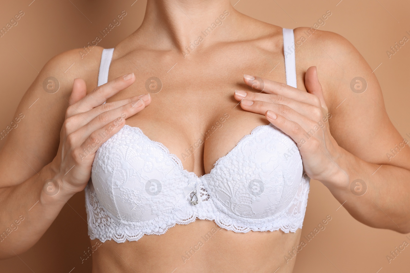 Woman wearing beautiful white bra on beige background, closeup Photo of Woman wearing beautiful white bra on beige background, closeup