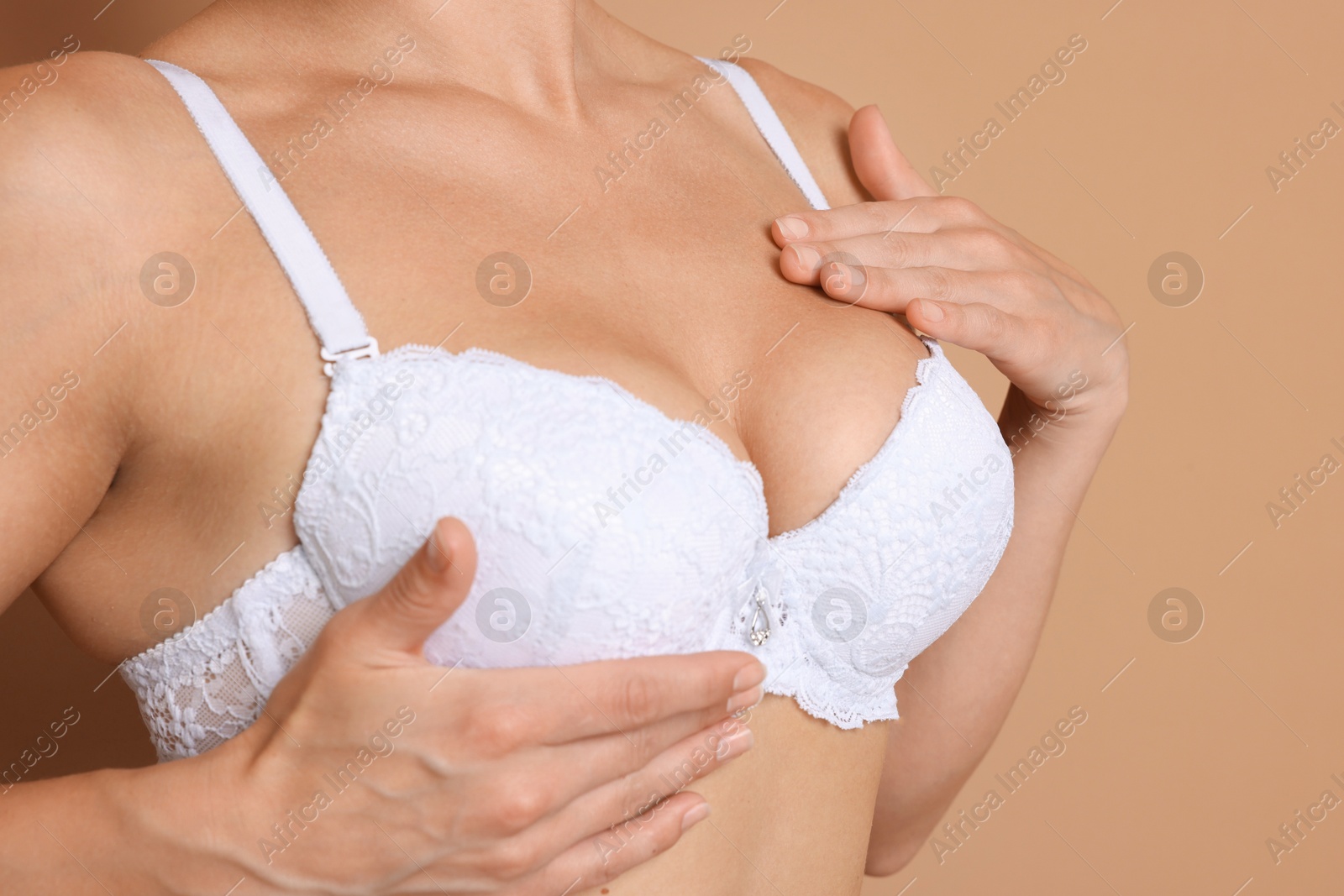 Woman wearing beautiful white bra on beige background, closeup Photo of Woman wearing beautiful white bra on beige background, closeup