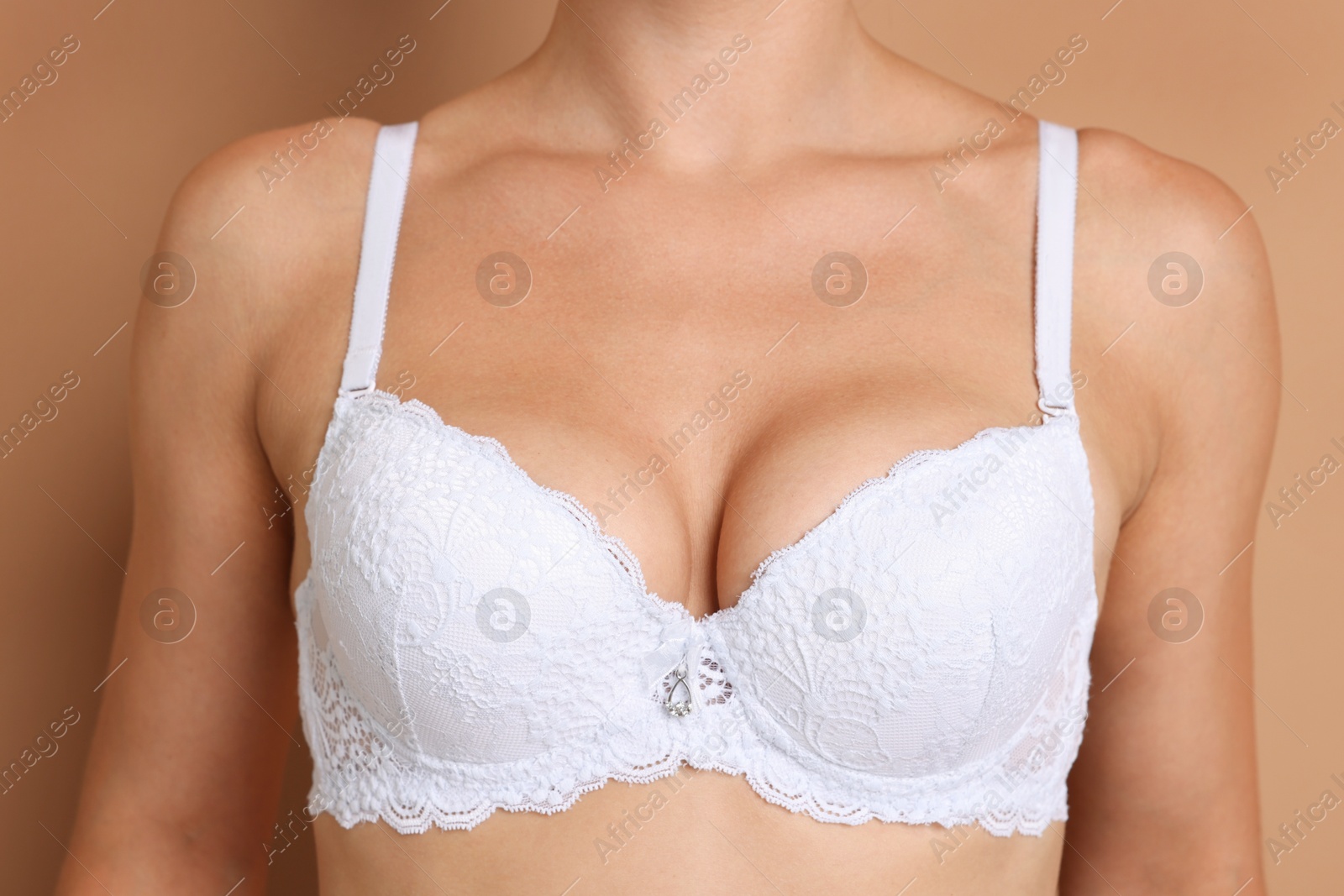 Woman wearing beautiful white bra on beige background, closeup Photo of Woman wearing beautiful white bra on beige background, closeup