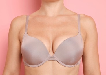 Photo of Woman wearing beautiful beige bra on pink background, closeup