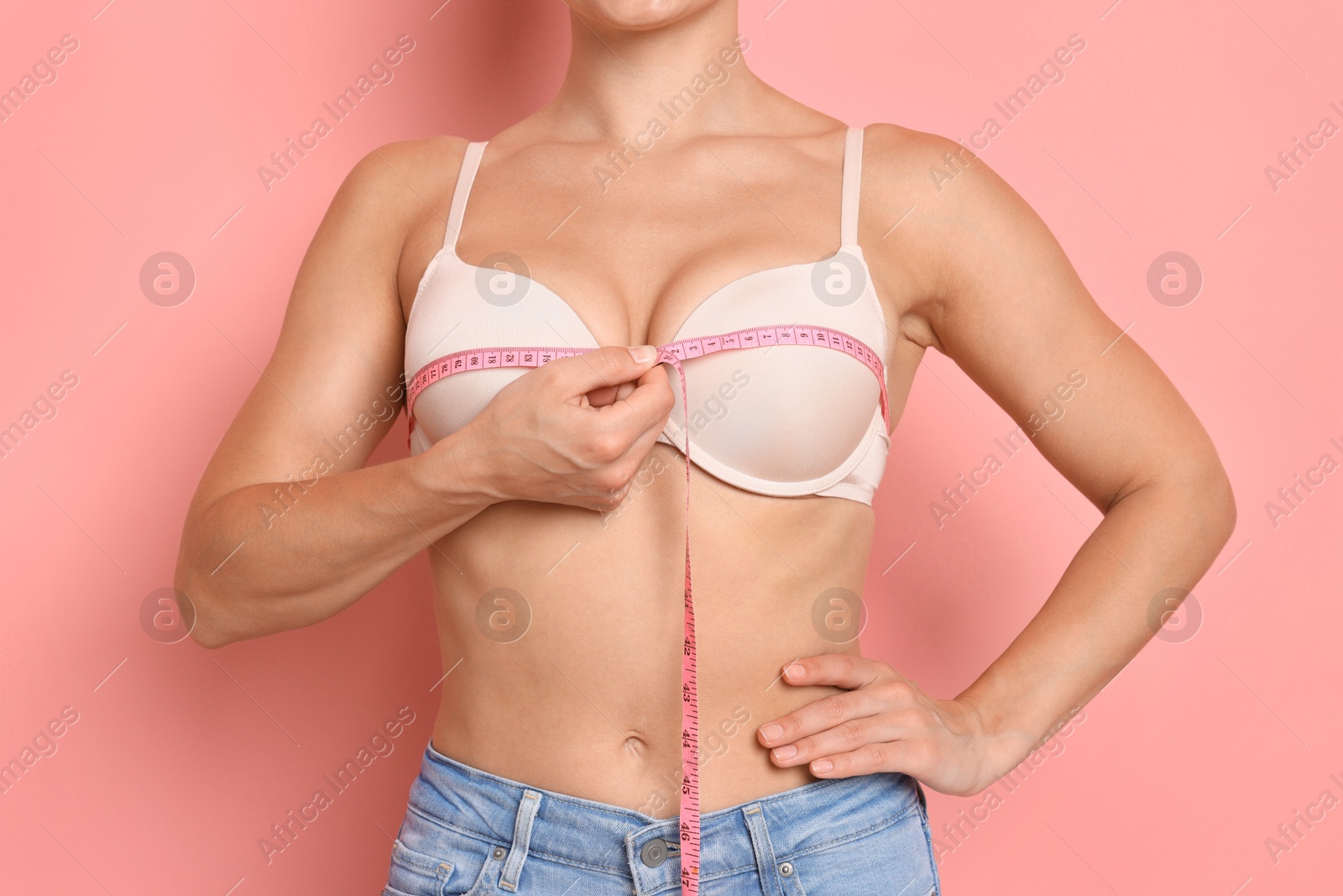 Woman in beautiful bra measuring breast circumference on pink background, closeup Photo of Woman in beautiful bra measuring breast circumference on pink background, closeup