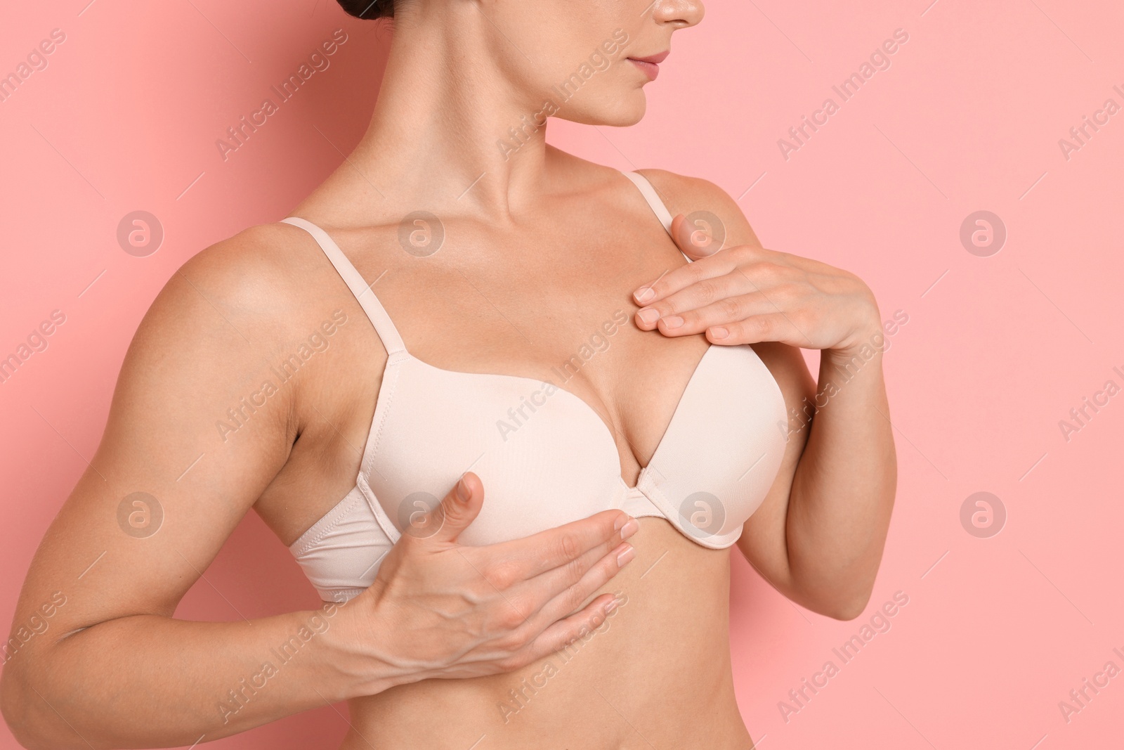 Photo of Woman wearing beautiful beige bra on pink background, closeup
