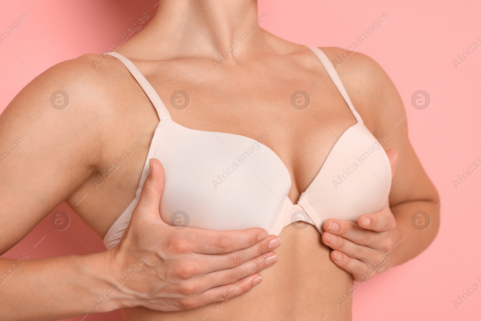 Woman wearing beautiful beige bra on pink background, closeup Photo of Woman wearing beautiful beige bra on pink background, closeup