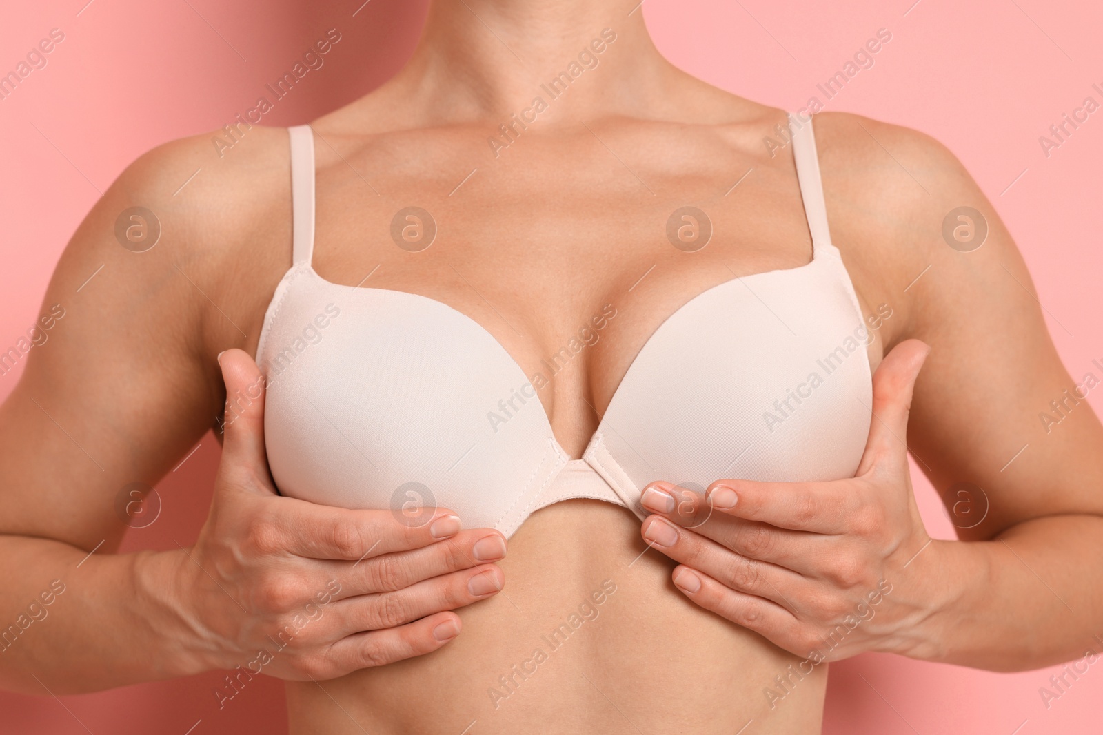 Woman wearing beautiful beige bra on pink background, closeup Photo of Woman wearing beautiful beige bra on pink background, closeup