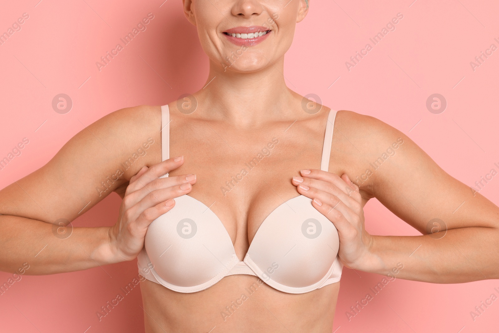 Woman wearing beautiful beige bra on pink background, closeup Photo of Woman wearing beautiful beige bra on pink background, closeup