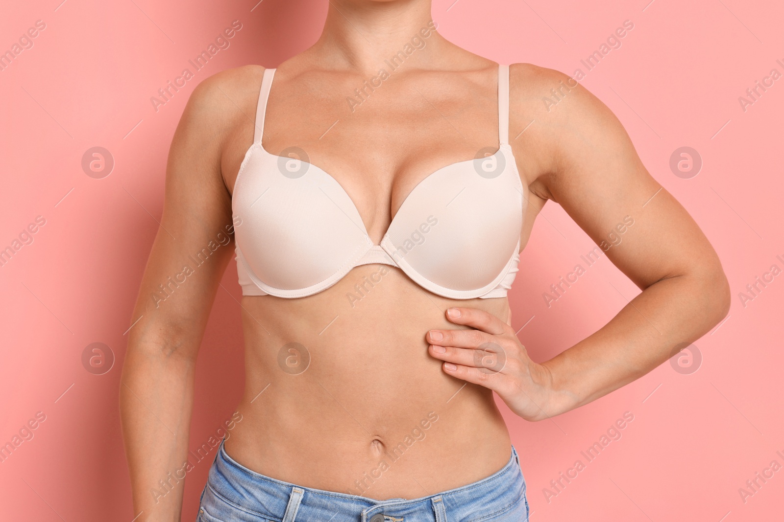 Photo of Woman wearing beautiful beige bra on pink background, closeup