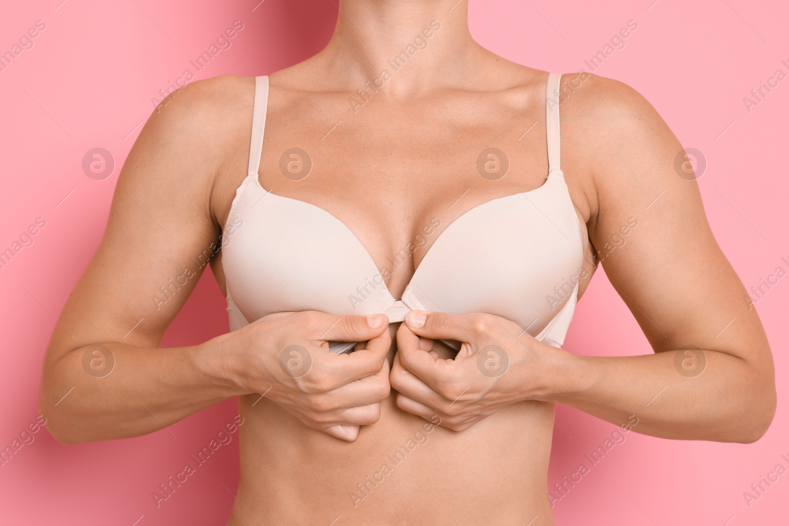 Woman wearing beautiful beige bra on pink background, closeup Photo of Woman wearing beautiful beige bra on pink background, closeup