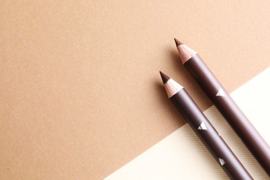 Photo of Different eyebrow pencils on beige background, top view. Space for text