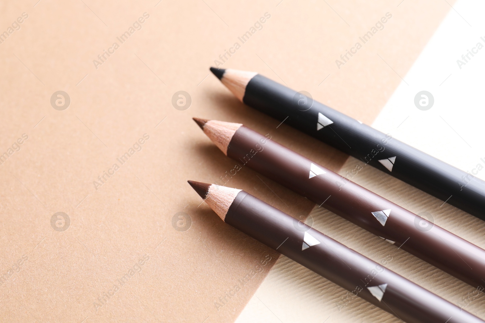 Different eyebrow pencils on beige background, flat lay. Space for text Photo of Different eyebrow pencils on beige background, flat lay. Space for text