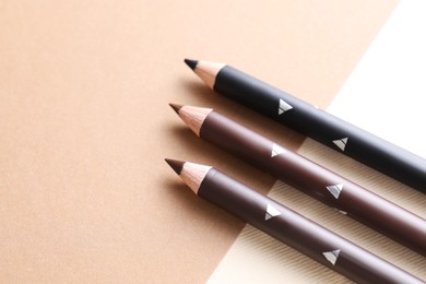 Photo of Different eyebrow pencils on beige background, flat lay. Space for text