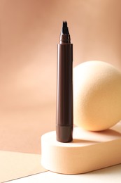 Photo of Stylish presentation of liquid eyebrow pencil on beige background, closeup