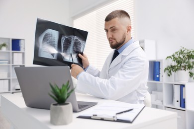 Photo of Doctor with lung MRI scan having online consultation via laptop in clinic