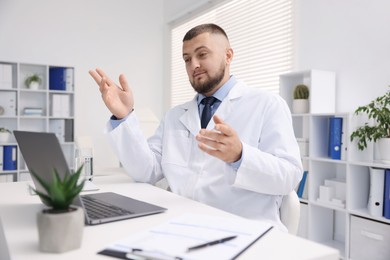 Photo of Doctor having online consultation via laptop in clinic