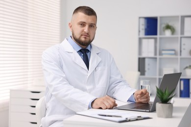 Photo of Doctor working at table with laptop in clinic. Online medical consultation