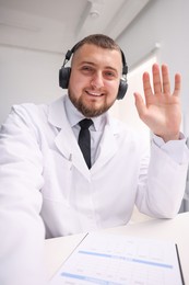Photo of Doctor in headphones having online consultation indoors