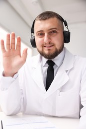 Photo of Doctor in headphones having online consultation indoors