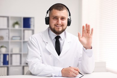 Photo of Doctor in headphones having online consultation indoors