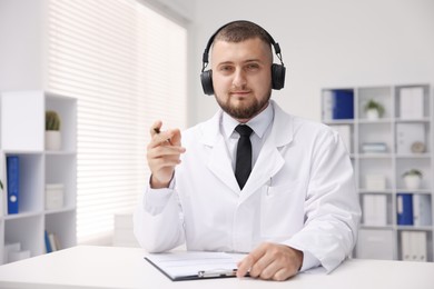 Photo of Doctor in headphones having online consultation indoors