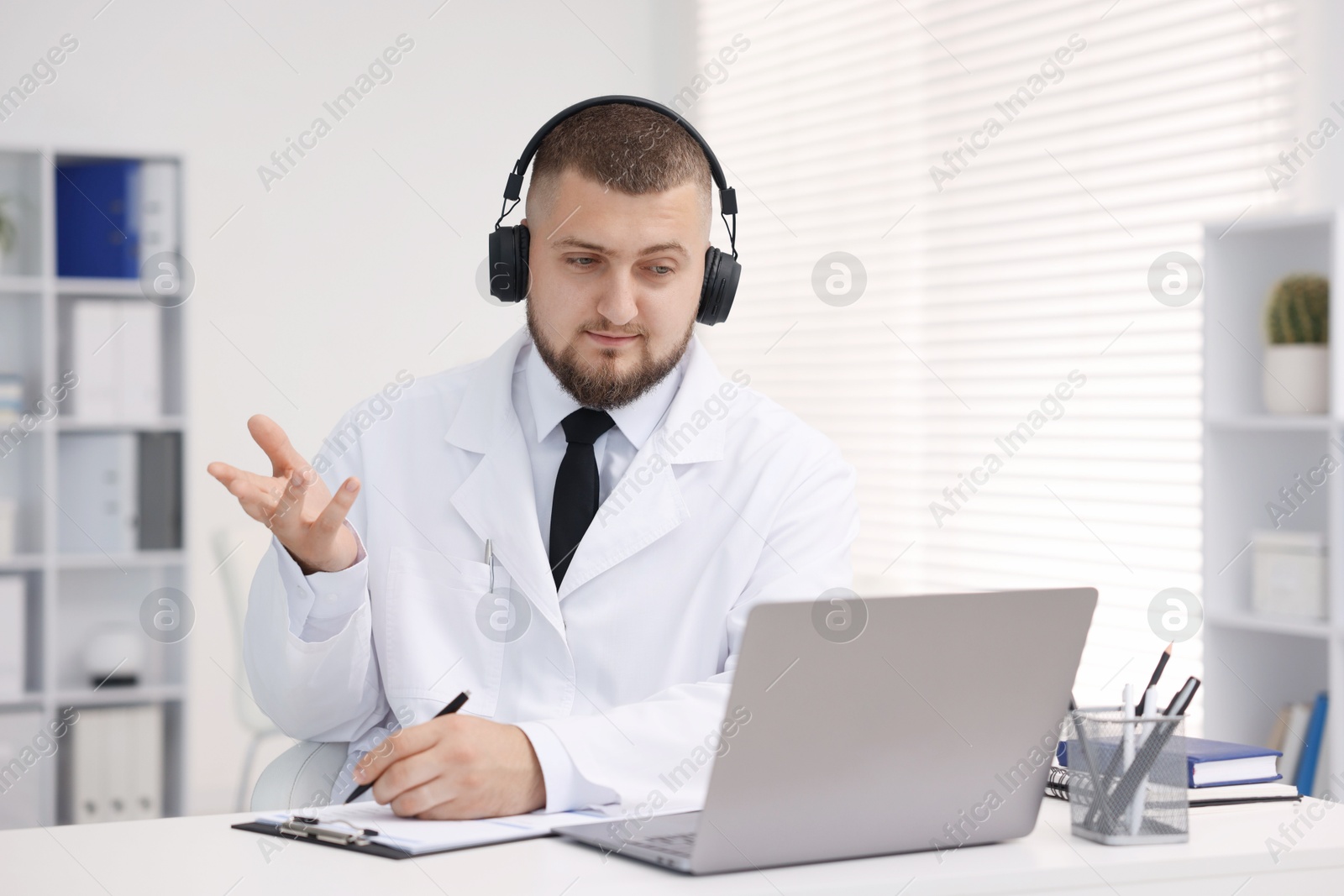 Doctor in headphones having online consultation via laptop indoors Photo of Doctor in headphones having online consultation via laptop indoors